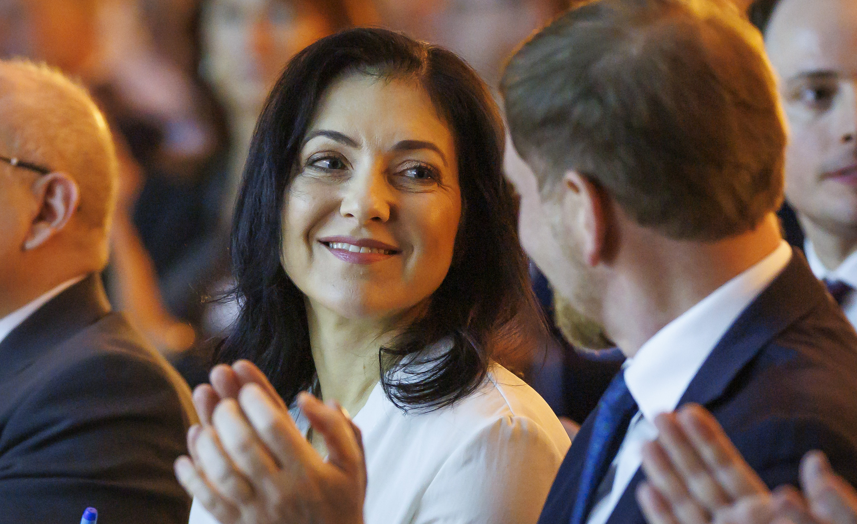 Katherina Reiche, frontally depicted, smiling and clapping in a crowd.